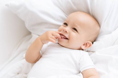 Mutlu erkek bebek beyaz yatakta