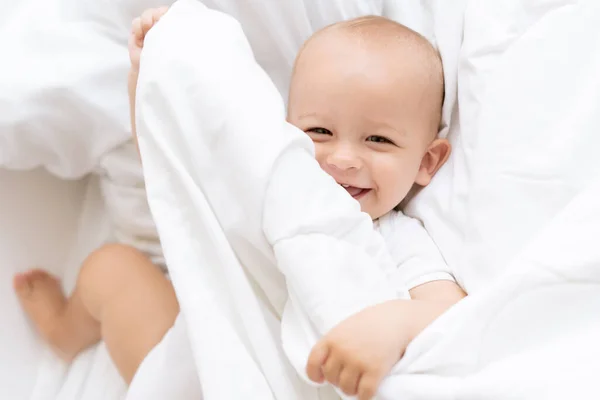 Baby Lacht Terwijl Hij Het Bed Ligt Verstopt Zich Onder — Stockfoto