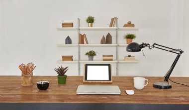 dizüstü ve tablet ahşap masa ve ofis iç. Kitaplık arka plan ev Aksesuar kitap, kahve ve bitkiler