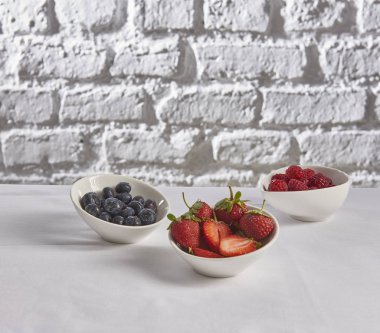 çilek, ahududu, tuğla duvar beyaz arka plan arkasında yaban mersini