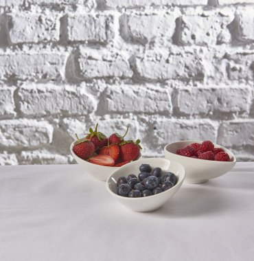 çilek, ahududu, tuğla duvar beyaz arka plan arkasında yaban mersini