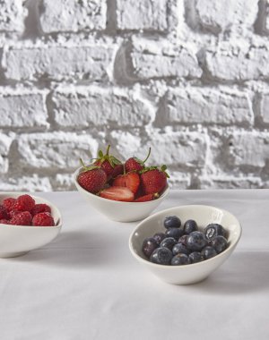 çilek, ahududu, tuğla duvar beyaz arka plan arkasında yaban mersini