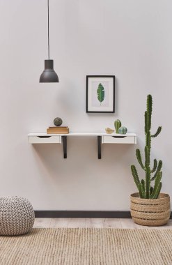 Beyaz asılı ahşap masa, çerçeve posteri, lamba, bitki tasarımı vazosu..