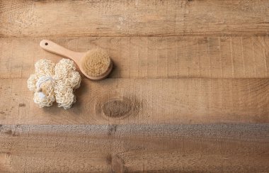 ahşap masa üzerinde banyo sabunu ve loofah fırça