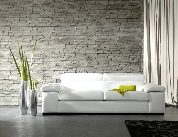 White sofa green blanket vase of plant and brick wall background.