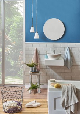 Modern banyo lavabo ayrıntı mavi duvar ve seramik tarzı ile. Dekoratif ayna ve lamba ile ahşap Oda ve beyaz küvette biz kat. Terlik, banyo Havlu nesnesinde
