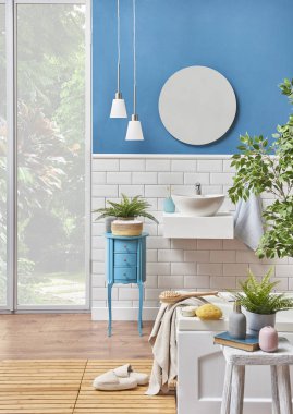 Modern banyo lavabo ayrıntı mavi duvar ve seramik tarzı ile. Dekoratif ayna ve lamba ile ahşap Oda ve beyaz küvette biz kat. Terlik, banyo Havlu nesnesinde