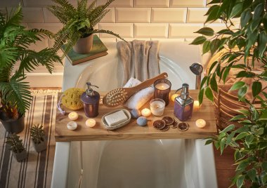 Modern banyo oda ve spa merkezi beyaz küvet ahşap masa. Mumlar, havlu ve sabun tarzı bitkiler ile. Beyaz mermer zemin duvar