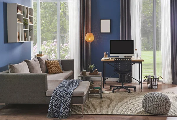 Modern room, blue wall, wooden desk and desktop room corner, sofa and computer