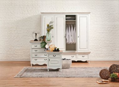 Beyaz klasik çekmece ve gardırop yatak odasında ve beyaz tuğla duvar arka planında..