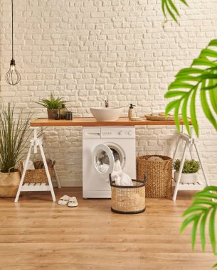 Banyo odasında çamaşır makinesi, çamaşır yıkama tarzı ve beyaz tuğla duvar arka planı, ahşap masa, halı ve lamba tarzı.