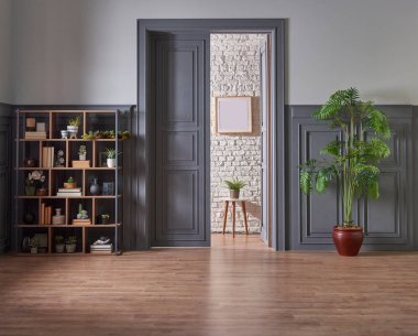 Klasik gri duvar ve kapı tarzında dekoratif ahşap kitaplık, yeşil bitkinin lamba çerçevesi ve vazosu.