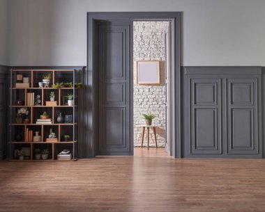 Klasik gri duvar ve kapı tarzında dekoratif ahşap kitaplık, yeşil bitkinin lamba çerçevesi ve vazosu.