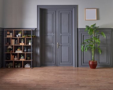 Klasik gri duvar ve kapı tarzında dekoratif ahşap kitaplık, yeşil bitkinin lamba çerçevesi ve vazosu.