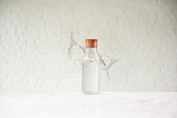 Брызги Воды Стеклянной Чашке Белом Столе Фоне Кирпичной Стены — стоковое фото