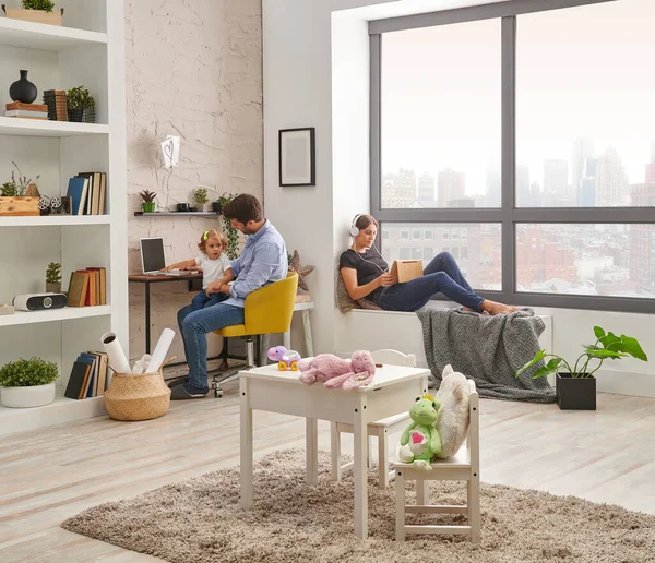 Dad mom and baby spend good time at home, working, looking tablet in the living room. Modern decorative wall and interior style.