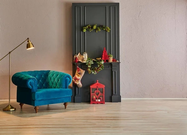 Christmas living room in front of the stone wall and grey classic fireplace, fir, gold lamp and blue armchair.