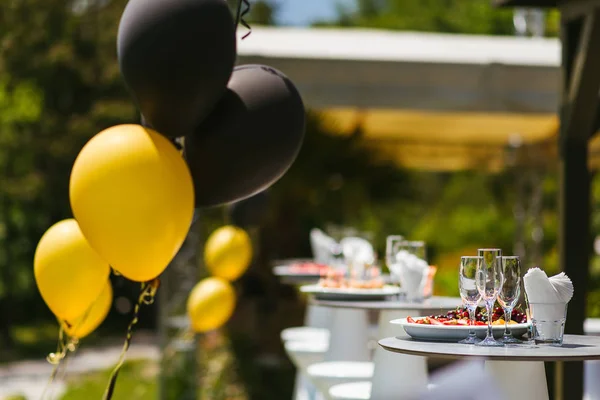 table setting with balloons for graduation party in black and gold