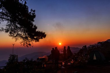 Siluet turist grubu dağın tepesinde durup San Pa Kia, Doi Mae Ta Man 'da güneşin doğuşunu bekliyorlar. Chiang Dao bölgesinde, Tayland' ın Chiang Mai bölgesinde. Kamp gezisi kavramı