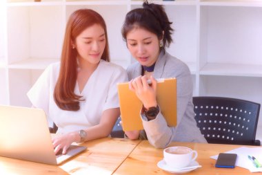 İki genç kız masadaki dizüstü bilgisayarla çalışmaktan zevk alıyor, yön ve ilham arıyorlar..