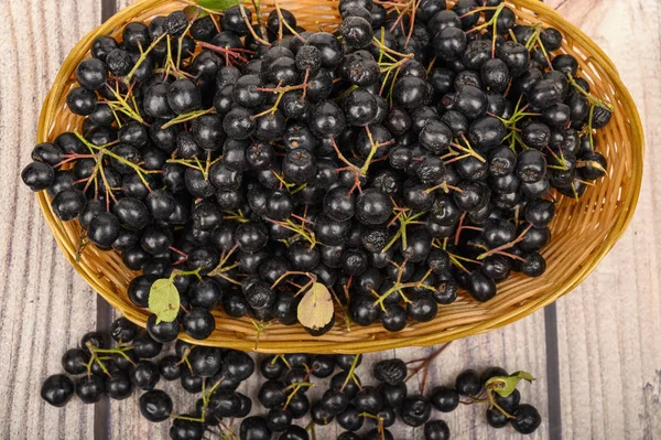 테이블에 고리 버들 바구니에 잘 익은 아로니아 열매 — 스톡 사진