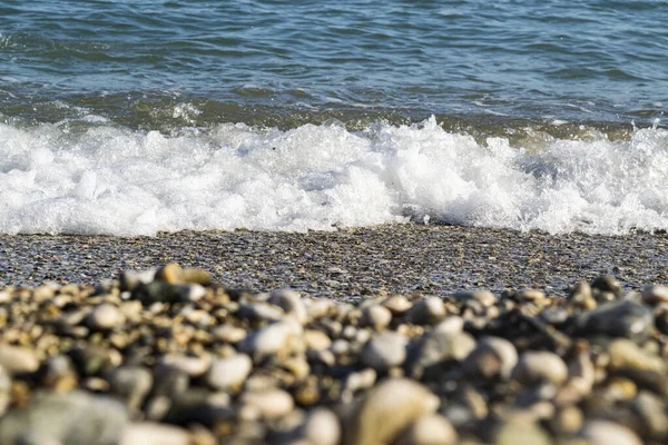 Vague de la mer sur une plage de galets, premier plan hors foyer . — Photo