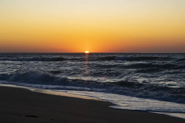 Sonnenaufgang über dem schwarzen Meer, Wellen am Sandstrand. — Stockfoto