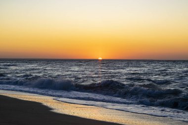 Karadeniz'de gün doğumu, kumlu sahilde dalgalar.