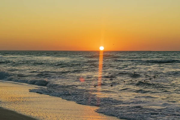 Sonnenaufgang über dem schwarzen Meer, Wellen am Sandstrand. — Stockfoto