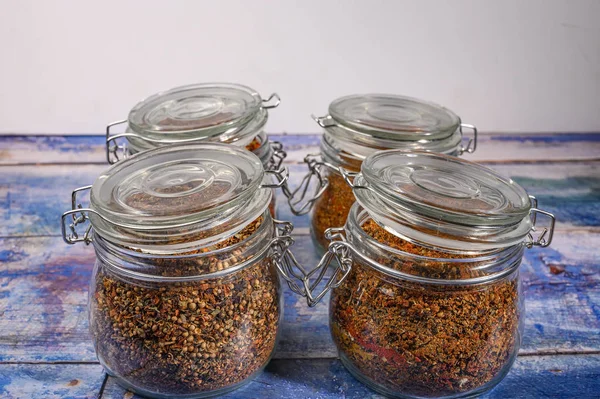 Fragrant spices in a glass jar with a lid and a metal lock on a wooden table. — Stock Photo, Image