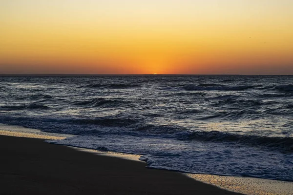 Sonnenaufgang über dem schwarzen Meer, Wellen am Sandstrand. — Stockfoto