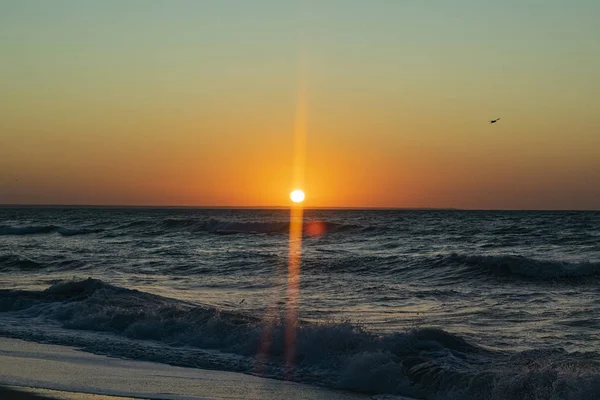 Sonnenaufgang über dem schwarzen Meer, Wellen am Sandstrand. — Stockfoto