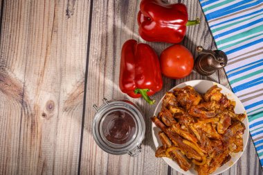 Masadaki baharatlarla marine edilmiş kuzu kaburgaları. Domates, tatlı biber ve bir kavanoz baharatla..