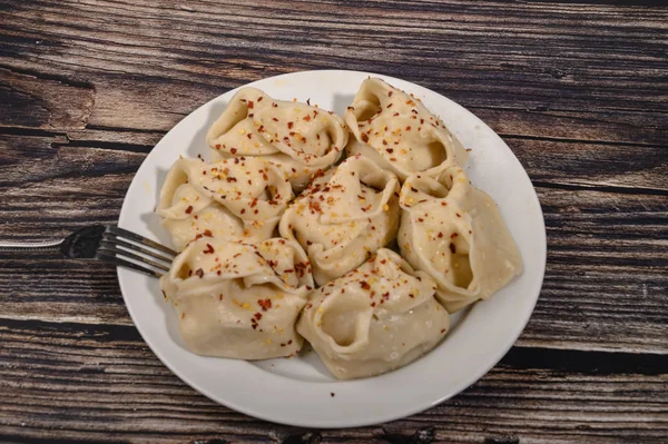 Boiled manti with beef on a plate with spices on a wooden table. — Stock Photo, Image