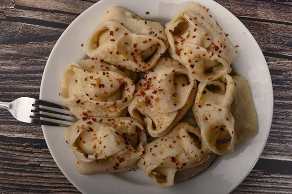 Boiled manti with beef on a plate with spices on a wooden table. Close up. — Stock Photo, Image