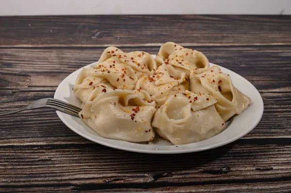 Boiled manti with beef on a plate with spices on a wooden table. — Stock Photo, Image