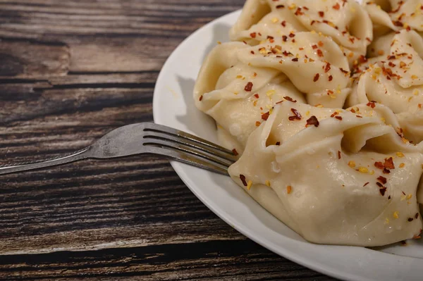 Boiled manti with beef on a plate with spices on a wooden table. Close up. — Stock Photo, Image