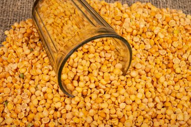 Kesik bir bardakta sarı bezelye ve kabarık desenli çuval bezelyesine saçılmış yulaf ezmesi. Çorba ve yulaf lapası yapmak için geleneksel mısır gevreği. Kapat.