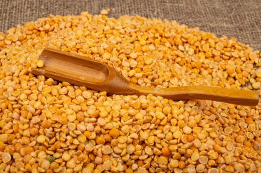 Kabataslak desenli çuval bezelyesine saçılmış sarı bezelyeler. Çorba ve yulaf lapası yapmak için geleneksel mısır gevreği. Kapat.