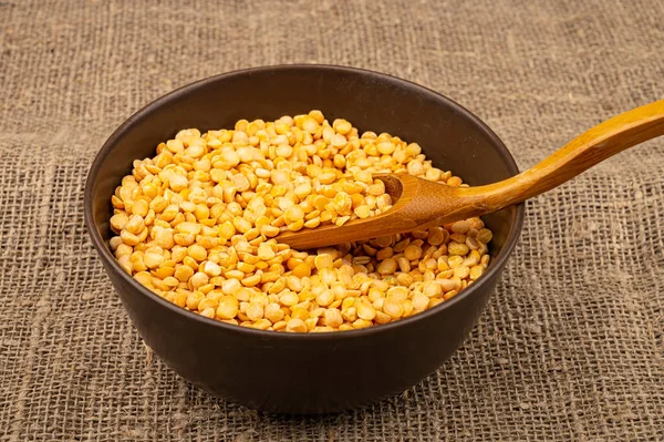 Yellow split peas in a ceramic bowl on a background of coarse-textured burlap. Traditional cereals for making soups and porridge. Close up — Stock Image Yellow Split Peas Ceramic Bowl Background Coarse Textured Burlap Traditional Royalty Free Stock Photos