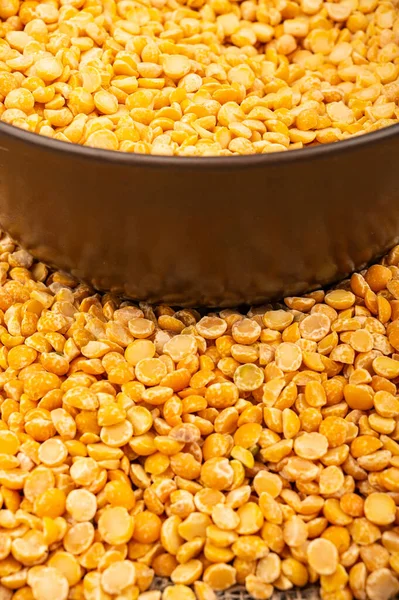 Yellow split peas in a ceramic bowl and grits scattered on a background of coarse-textured burlap. Traditional cereals for making soups and porridge. Close up — Stock Image Yellow Split Peas Ceramic Bowl Grits Scattered Background Coarse Textured Royalty Free Stock Images