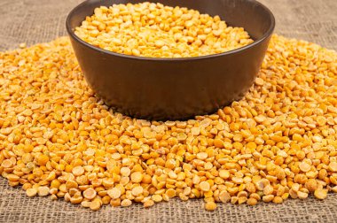 Seramik bir kasede sarı bezelye ve kabarık desenli çuval bezelyesine saçılmış mısır ezmesi. Çorba ve yulaf lapası yapmak için geleneksel mısır gevreği. Kapat.