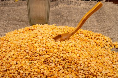 Kabataslak desenli çuval bezelyesine saçılmış sarı bezelyeler. Çorba ve yulaf lapası yapmak için geleneksel mısır gevreği. Kapat.