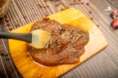 Kesme tahtasında marine edilmiş et, sarımsak, baharat, baharat. Kapat.