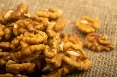 Kaba desenli çuval bezi kaplı ahşap bir masanın üzerinde ceviz kabuğu soyulmuş. Sağlıklı beslenme. Fitness diyeti. Kapat.