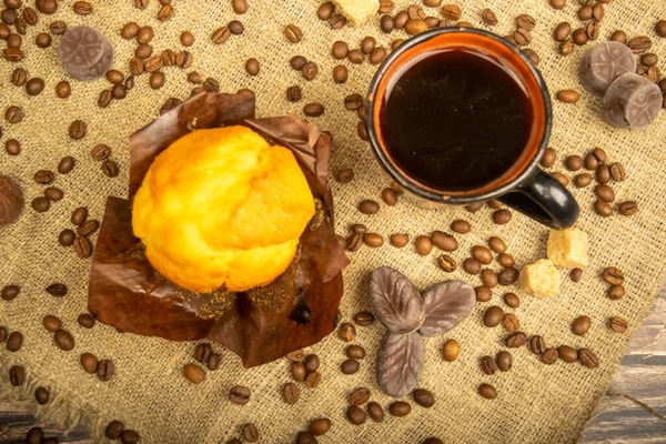 Frischer Cupcake Kaffeebecher Pralinen Und Kaffeebohnen Auf Einem Selbstgesponnenen Stoff — Stockfoto