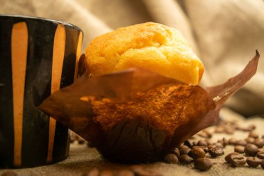 Taze kek, kahve fincanı ve ev yapımı kabataslak kumaşlı kahve çekirdekleri. Kapat.