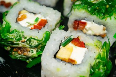 Balık, peynir ve yeşil yosunlu rulo. Geleneksel bir Japon yemeği. Kapat.