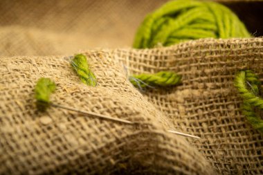 Kaba desenli çuval bezi üzerinde bir top yeşil iplik. Kapat.