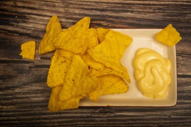 Tahta arka planda peynir soslu mısır cipsi. Kapat.